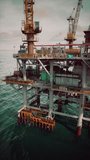 An aging oil rig stationed in the vast expanse of the ocean, operating to harvest resources.