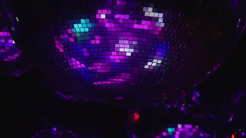 A disco ball with purple and blue lights. Scene is fun and energetic. The disco ball is the main focus of the image, and the lights surrounding it create a vibrant and lively atmosphere. Part of