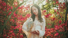 Happy charming teenager girl fashion model posing with white barn owl bird. beauty face. forest red leaves nature. Lady fairy tale elf princess dress, sunset sun rays light flare, high quality 4k.