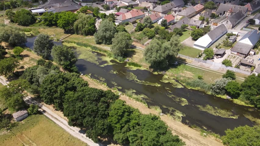 Stagnant canal running through small village of Batya, Hungary, aerial view.