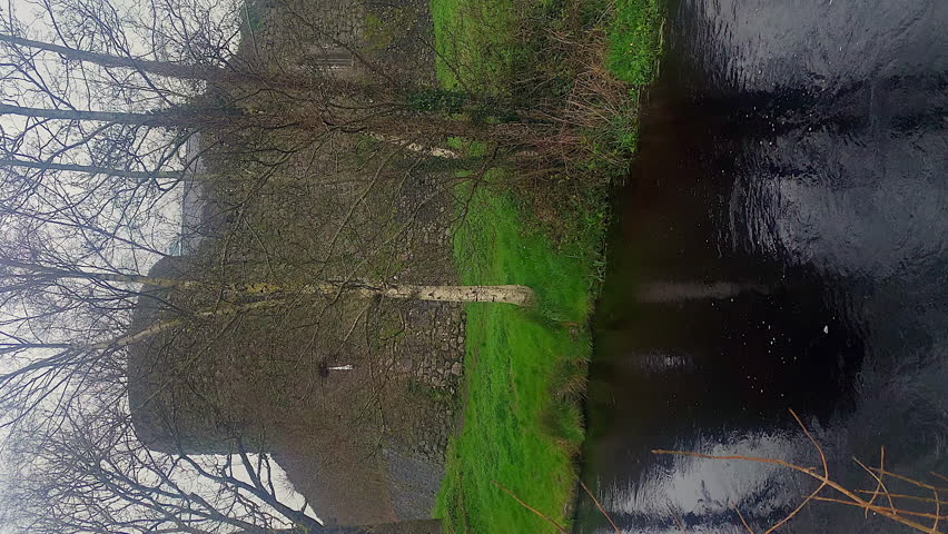 Athenry Castle. Symmetrical reflexion on the Clarinbridge river. Rainy day.