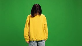 Emotional woman with short haircut in oversized shirt delight expression raised hands against vibrant green studio background. Concept of human emotions, fashion, beauty, style.