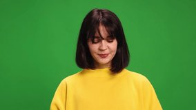 Close-up of young emotional brunette woman in oversize yellow shirt loudly shouting and laughing against green studio background. Concept of human emotions, fashion and beauty, style. Ad