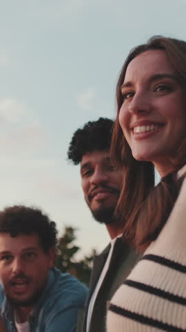 Vertical video, Guys and girls at the party, looking at the beautiful views and talking standing on the terrace, friendly party holiday at sunset