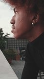 Vertical video, Close-up of young guy is standing on the balcony looking at the city