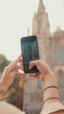 Vertical video, Close up, traveler girl, with backpack on her shoulders, takes photo on mobile phone of an old building in the historical part of European city