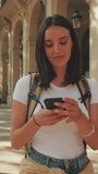 Vertical video, Traveler woman walking down the street with phone in her hands