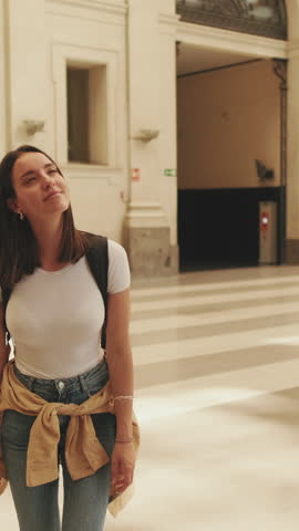 Vertical video, Beautiful girl traveler looks at the train schedule at the railway station