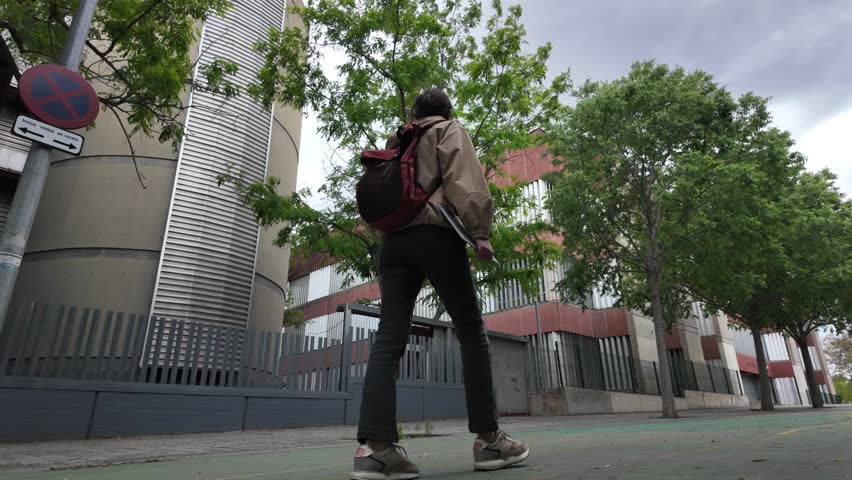 A Latin-American woman strolls through the university campus with her laptop and backpack on a sunny day, heading to classes. University student life, education, and future