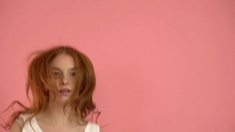 Girl teenager with red hair jumping on a pink background
