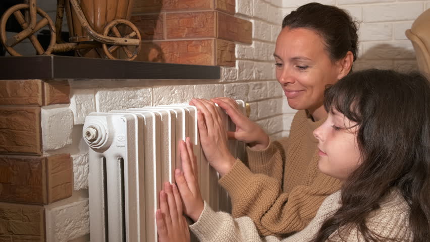 Family warm together by radiator. A family with smile on her face sitting on the floor and resting by the central heating system.