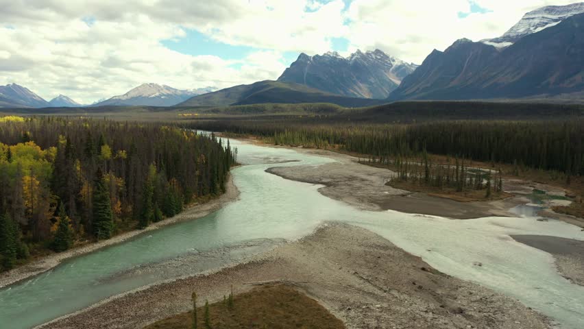 Aerial view of the Athabasca River with its bluish color surrounded by thousands of trees, on a fall day in Alberta, Canada.