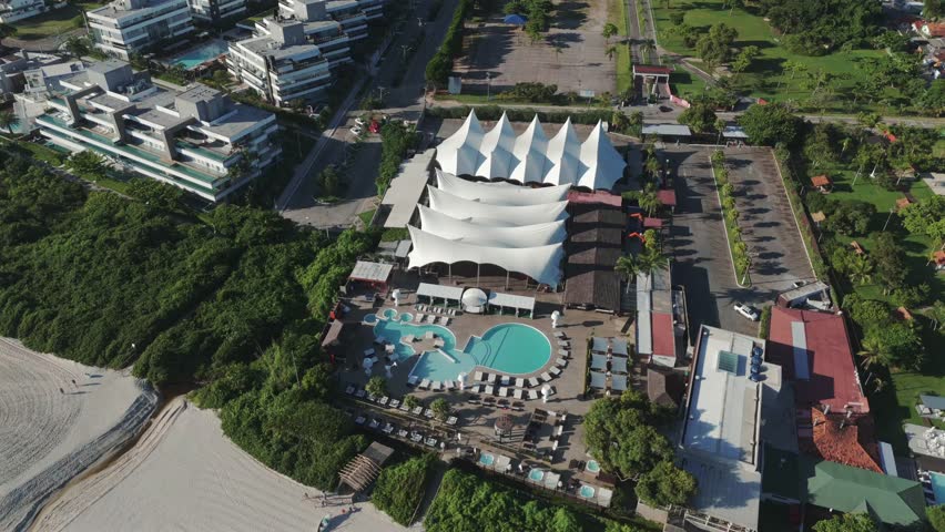 A drone circling around P12, showcasing its marvelous facilities for parties and events in Jurerê Internacional Beach, Florianópolis.