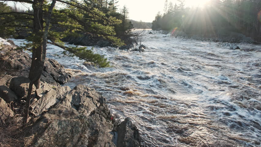 Sunlight beams illuminating a swollen river from spring snowmelt in northern Minnesota