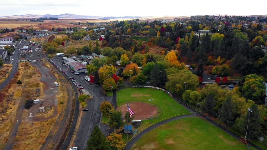 Aerial Panning Shot Of U.S Flagpole In Residential Town On Hill - Rural, Idaho