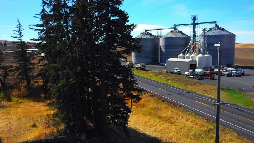 Aerial: Drone Upward Shot Of Silos On Tranquil Hill Against Sky During Sunny Day - Rural, Idaho