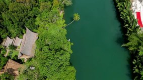 4K Aerial drone video of emerald Loboc river with riverside road and houses and sheds in Bohol, Philippines