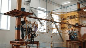 The general plan inside the premises of the rope park. A strong little girl of 10 years old demonstrates her bravery and determination, passes an obstacle course in protective equipment. 4k footage - Powered by Shutterstock - Get 15% off with code: PIKWIZARD15