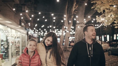 A happy family walks the evening in the city on holidays