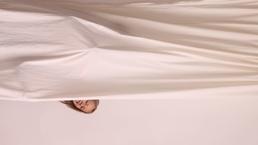 Three girls peek out from behind a curtain against a white wall. Concept: family bonding, child development ads, copy space.