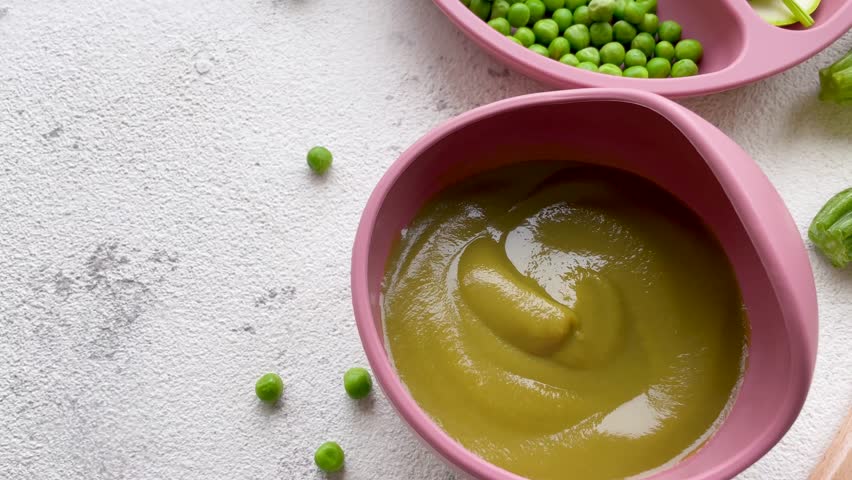 Healthy baby food in bowl. Baby food vegetable puree with broccoli and peas