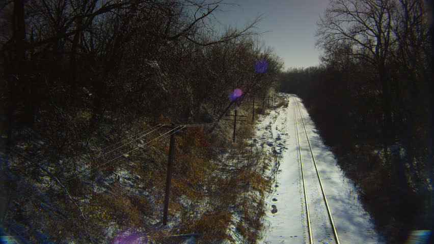 Shadows of barren trees crawl over snow-covered railroad tracks in a woodlands wonderland after a severe ice storm.