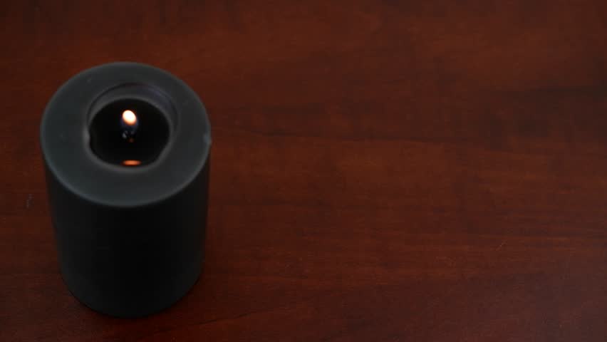 Burning black candle and runes on wooden table. Human hand choosing different runes, fortune telling concept.