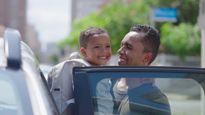Father carries son on his arms outside the car
