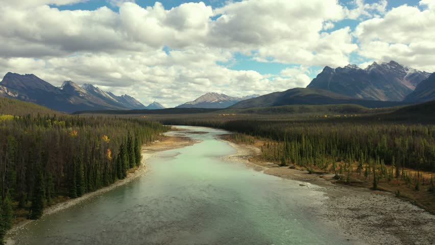 Aerial view of the Athabasca River with its bluish color surrounded by thousands of trees, on a fall day in Alberta, Canada.