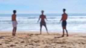Holiday at the beach. Blurred silhouettes of young people playing volleyball at the beach.