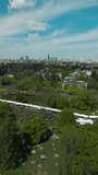 city street food festival event at green park at summer, tents of food market at green meadow, crowd walking and sitting at picnic, aerial view 4k, vertical video footage