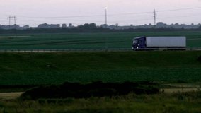 Journey's End: Panning Side View of White Truck Approaching Destination on Road with Green Grass (4K Video)