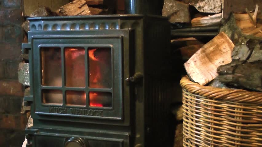Adding wood to a stove - Man putting logs onto a fire