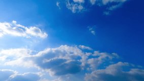 Soft fluffy clouds are lit with bright summer sun. Beautiful cloudscape transforms in the sky. Low angle view. Timelapse.
