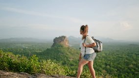 Mature Asian woman hikes rocky path, explores Sigiriya Rock at sunset. Senior hiker enjoys eco travel, wellness adventure. Active old traveler with backpack admires mountain view, healthy lifestyle. - Powered by Shutterstock - Get 15% off with code: PIKWIZARD15