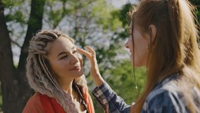 Lesbian happy woman applies glitter to the face of her girlfriend with curly hair, lgbt parade - Powered by Shutterstock - Get 15% off with code: PIKWIZARD15