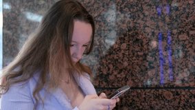 young girl works uses phone on the background of a stone wall