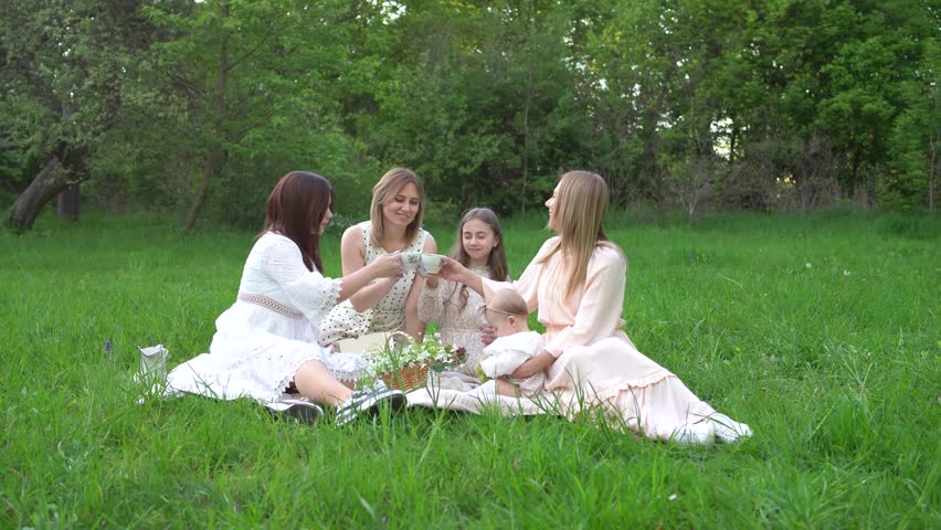 the two women and their children having a picnic on a lawn
