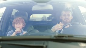 Happy father singing song while driving car with his little son. Slow motion - Powered by Shutterstock - Get 15% off with code: PIKWIZARD15
