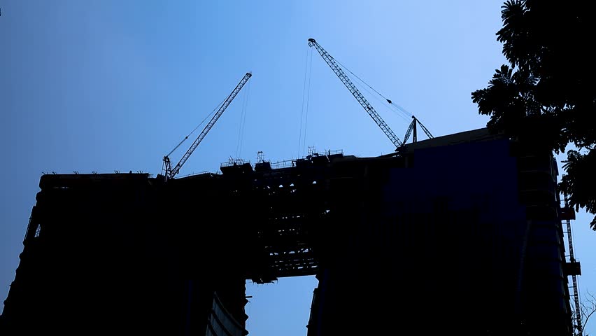 Silhouette of a towering construction crane It was a construction crane moving against the bright blue sky.
