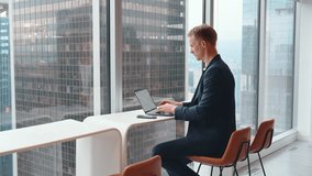 Busy professional business man employee, young male executive, businessman entrepreneur wearing suit typing on laptop computer using mobile phone working at office coworking near big window. - Powered by Shutterstock - Get 15% off with code: PIKWIZARD15