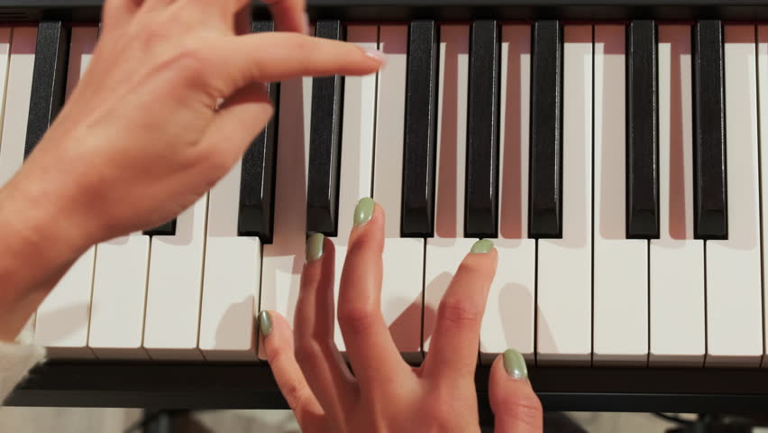 Female fingers press keys on piano under teacher control closeup. Woman tutor corrects student mistakes offering right sequence slow motion Royalty-Free Stock Footage #3494460545