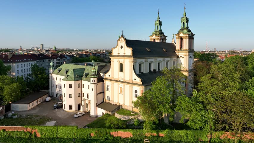 Krakow, Poland. Skalka, St. Stanislaus Baroque church na Skałce, Paulinite monastery, Vistula river. Aerial 4K revealing video in spring. People walking, running and biking on boulevard and promenade