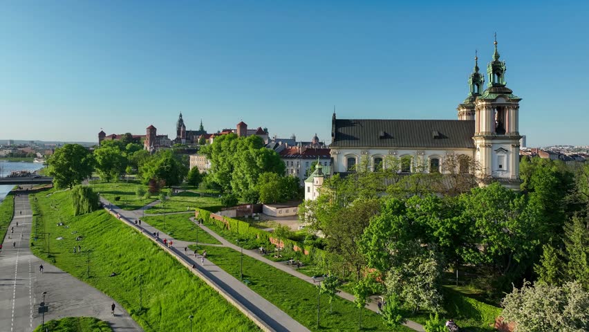 Krakow, Poland. Skalka, St. Stanislaus Baroque church na Skałce and Paulinite monastery. Aerial panning video in spring. People walking on boulevard and promenade. Old town and Wawel in the background