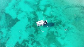 Aerial Drone Overhead view of beautiful blue lagoon with sailing boat, people swimming and birds flying around, Aruba, Caribbean sea