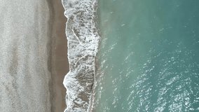 Person walking along Pissouri Beach, Cyprus island. Aerial top-down backward