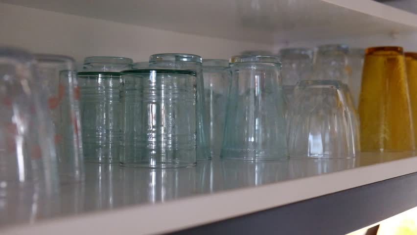 Close Up View Of water Glasses Being Sorted In Kitchen. Placing the water glasses on the shelf. Replacing the cleaned glasses on the place. put the water glass on the shelf.
