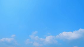 A cloud timelapse in summer unveils the journey of white clouds across a clear blue sky, symbolizing the fluidity of nature. Nature movement concept. High-quality video. Time lapse. Sky background.
