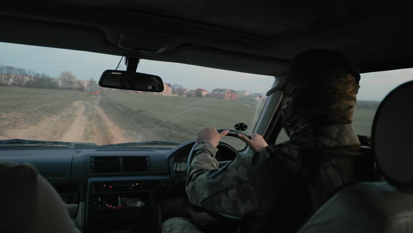 Soldier Driving on Rural Road at Dusk, Military personnel driving a vehicle through rural terrain at twilight.