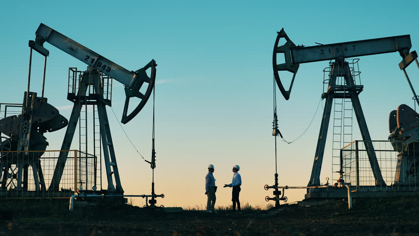 Technicians are talking between two oil pumping units. Oil industry concept.